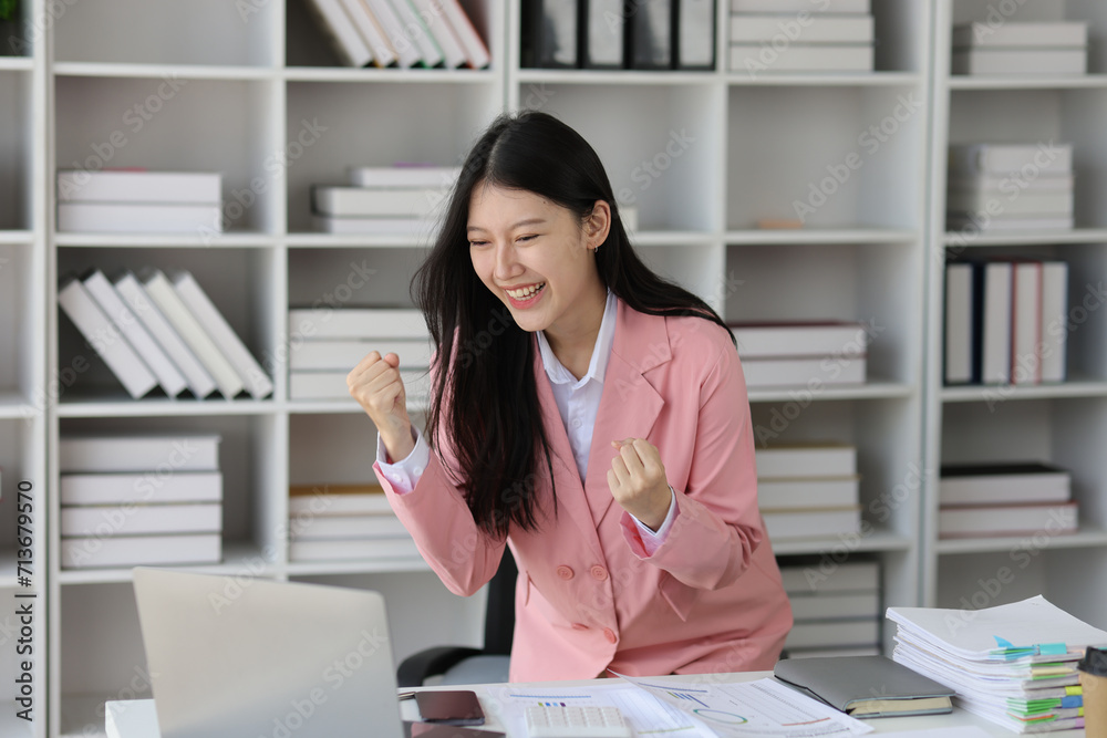 Successful Asian businesswoman happy looking at laptop and excited.