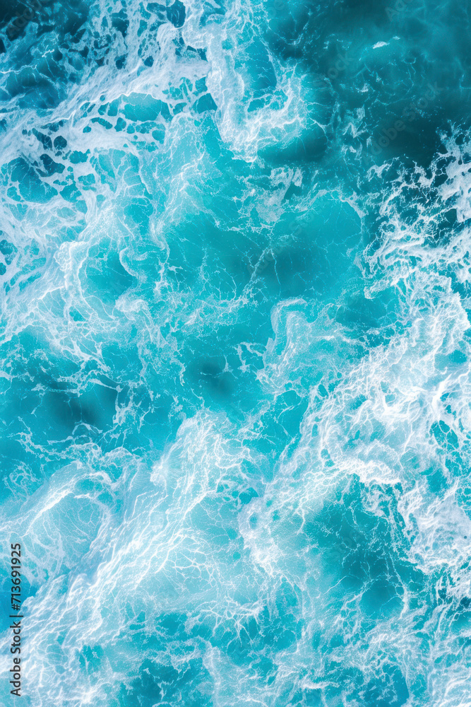 Vertical  aerial view from above of turquoise ocean water with splashes and foam for abstract natural background and texture.