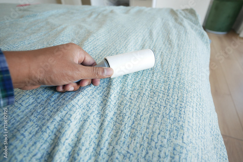 using an adhesive roller to remove lint and fluff from a bed . photo
