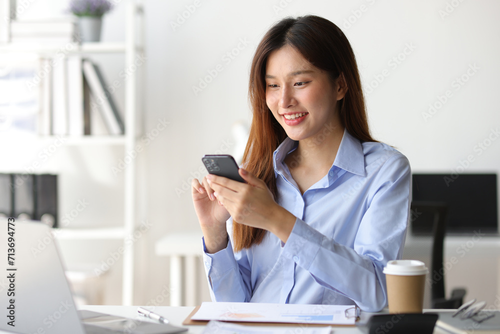 Asian woman in office is using mobile phone and calling someone, she is smiling with joy and surprise when receiving good news. Asian woman in office is using mobile phone and calling someone, she is smiling with joy and surprise when receiving good news.