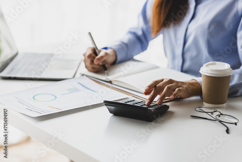 Businesswoman working on financial documents on the desk in the office is writing notes and calculating income and expenses.