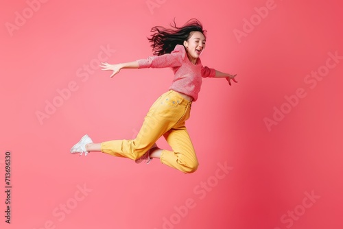 Lively Asian model in summer style, mid-leap with a kiss, coral pink studio background