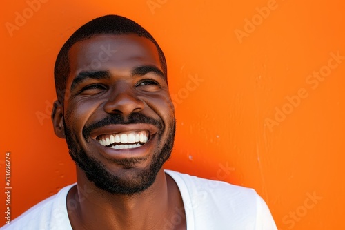 Man with beaming smile, laughing, close up, orange background