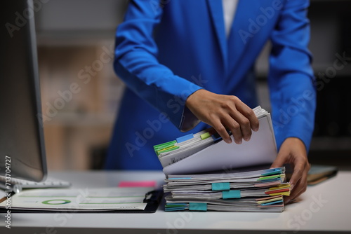 Businesswoman hands working in Stacks of paper files for searching and checking unfinished document achieves on folders papers at busy work desk office.