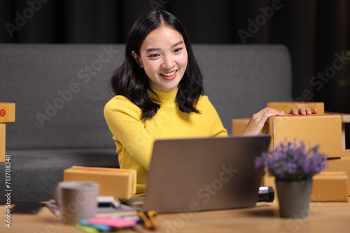 A young Asian woman started an online sales business as a part-time job, She is working with shipping boxes to prepare for home delivery of an internet order.