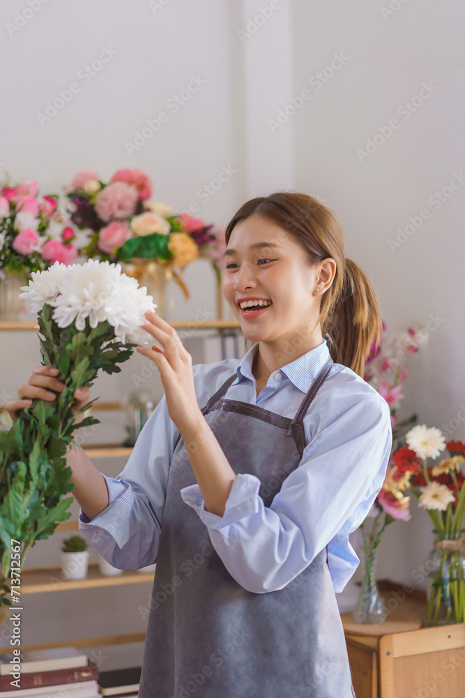 Floristry concept, Woman florist holding white chrysanthemum with smiling happiness in flower shop Floristry concept, Woman florist holding white chrysanthemum with smiling happiness in flower shop
