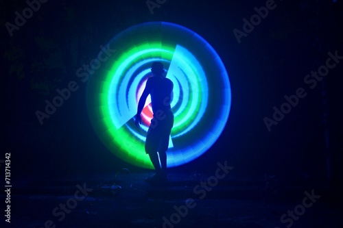 One person standing alone against a Colourful circle light painting as the backdrop 