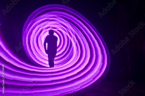 One person standing alone against a Colourful circle light painting as the backdrop 