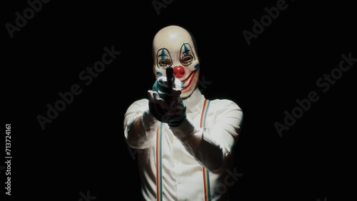 Man with scary clown mask on his face and He points a gun at the camera photo