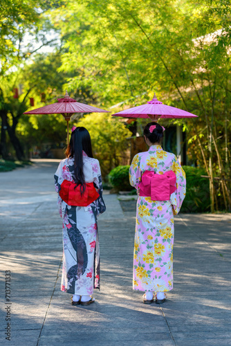 Back view of a young woman wearing a Japanese Yukata and holding a paper umbrella.