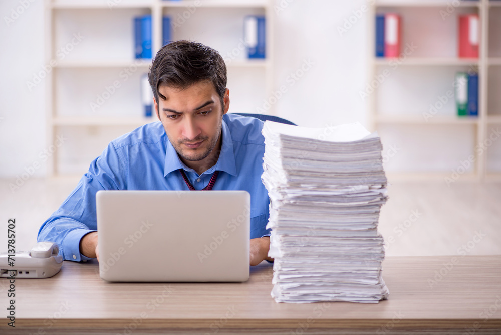 Young male employee and too much work in the office Young male employee and too much work in the office
