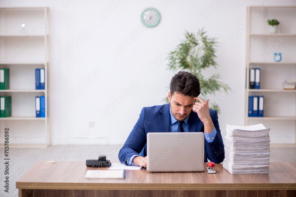 Young male employee and too much work in the office Young male employee and too much work in the office