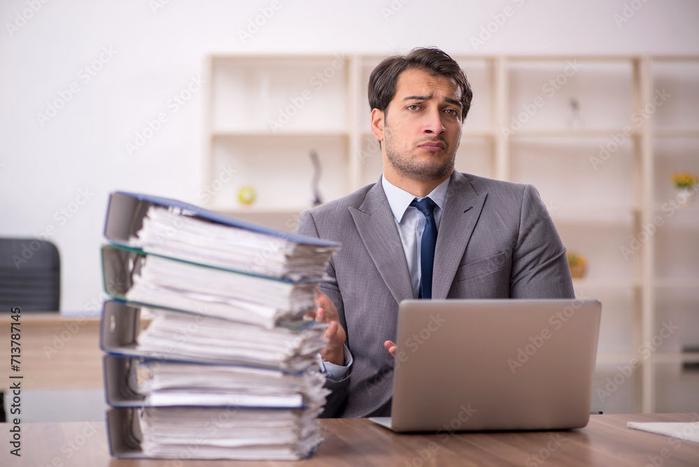 Young male employee and too much work in the office Young male employee and too much work in the office