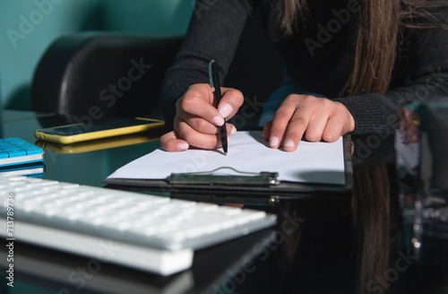Caucasian woman writes in clipboard at home.