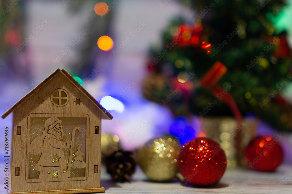Decorations for Christmas and New Year: wooden house with Santa Claus against bokeh blured background with balls, garlands and xmas tree