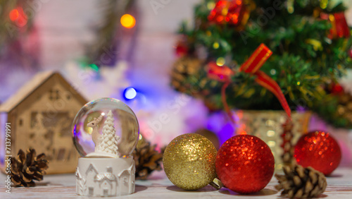 Decorations for Christmas and New Year: colorful balls against small wooden house, xmas tree and snowflakes. Blured bokeh background