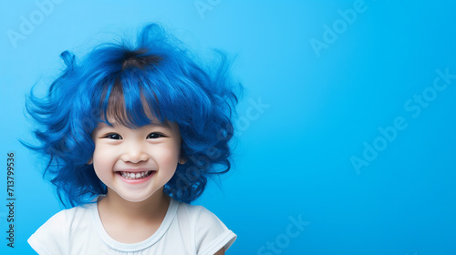 Cheerful girl with vibrant blue hair smiling in professional studio with monochrome background