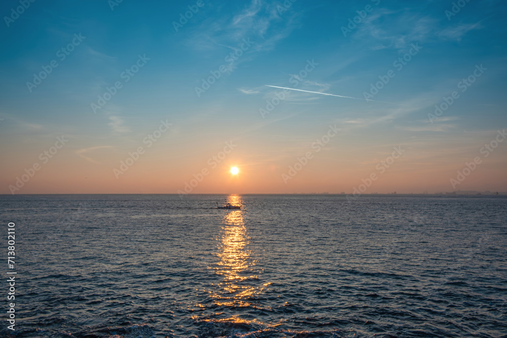 small fishing boat going in the open sea at sunset