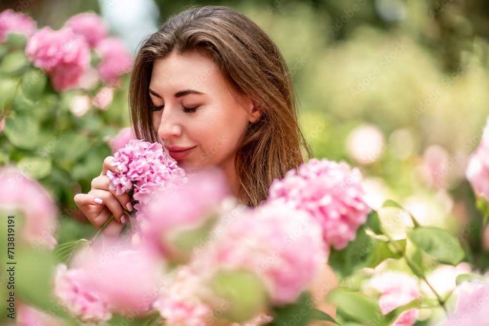 Hydrangeas Happy woman in pink dress amid hydrangeas. Large pink hydrangea caps surround woman. Sunny outdoor setting. Showcasing happy woman amid hydrangea bloom. Hydrangeas Happy woman in pink dress amid hydrangeas. Large pink hydrangea caps surround woman. Sunny outdoor setting. Showcasing happy woman amid hydrangea bloom.