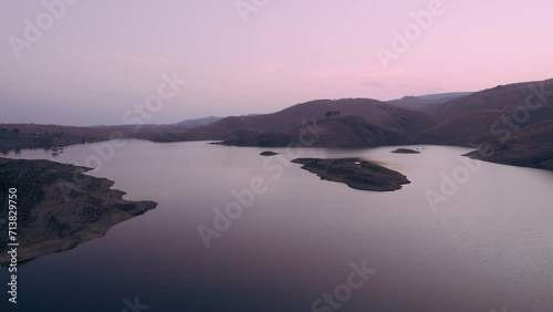 aerial drone shot flying forward over alsigarh lake surrounded by aravalli hills near udaipur city a popular tourist destination during sunrise sunset photo