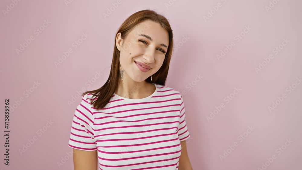 Stylish young brunette girl in a striped tshirt flashes a cool, confident smile of success, radiating joy and happiness. truly proud and positive, she beams over an isolated pink background. Stylish young brunette girl in a striped tshirt flashes a cool, confident smile of success, radiating joy and happiness. truly proud and positive, she beams over an isolated pink background.