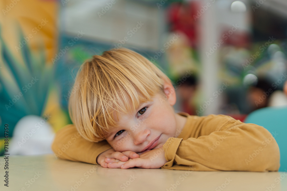 Fototapeta premium boy sitting on chair at the table, his head resting on his hands