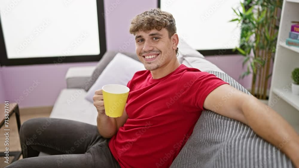 At home, a confident young hispanic man enjoys a morning cup of coffee, comfortably relaxed on the sofa. his handsome expression radiating positivity and joy from his infectious, heartwarming smile. At home, a confident young hispanic man enjoys a morning cup of coffee, comfortably relaxed on the sofa. his handsome expression radiating positivity and joy from his infectious, heartwarming smile.