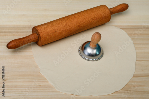 Ciasto na pierogi leży obok drewnianego walka, wycinać okrągły kształt 