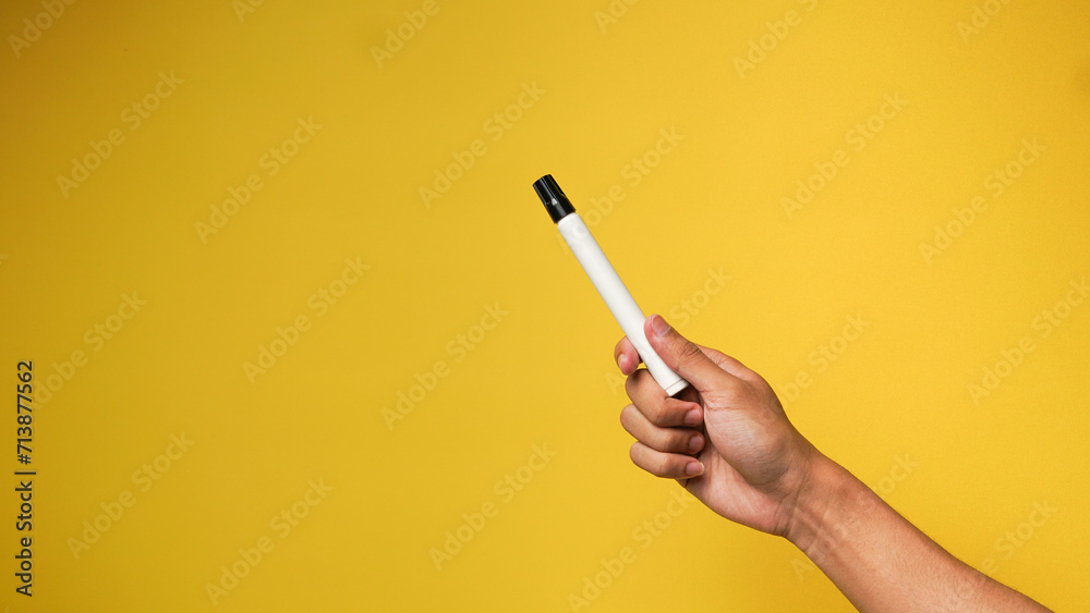 Man's hand holding a black marker on a yellow background Man's hand holding a black marker on a yellow background