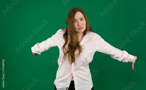 Happy satisfied curly blonde girl gives hug at camera, spreads hands, meets with close friend, dressed casually walked against green . High quality photo © Oleksandra