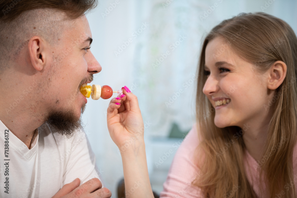A smiling blonde woman feeds her boyfriend from her hand. A smiling blonde woman feeds her boyfriend from her hand.