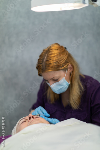 The cosmetologist performs needle mesotherapy on the client's face.