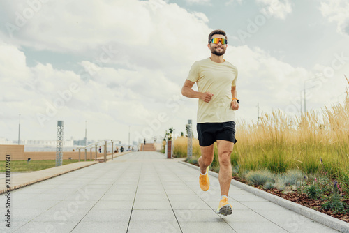 Active man in sportswear enjoys a run in a sunny urban park.