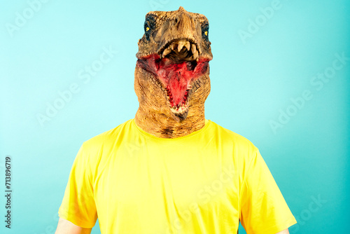 Fototapeta Naklejka Na Ścianę i Meble -  Person in Dinosaur Costume Mask Yellow T-Shirt Blue Background
