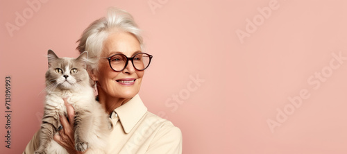 Happy senior lady with fashion Abyssinian cat on beige background. Human and pet. Panorama