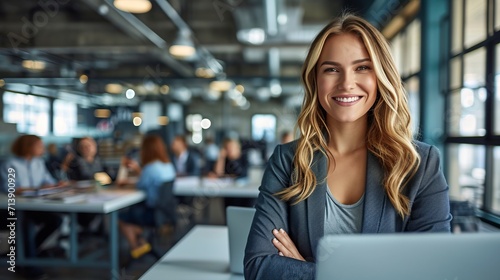 Cheerful middle aged businesswoman in blue suit working on laptop at office desk