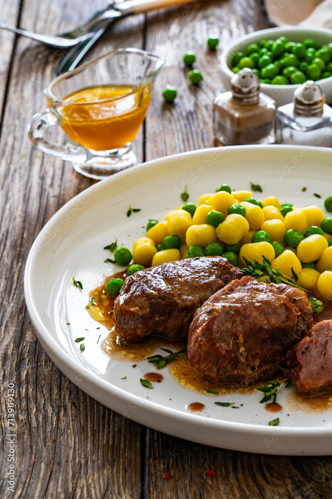 Baked pork cheeks in sauce with gnocchi and green peas on wooden table
Baked pork cheeks in sauce with gnocchi and green peas on wooden table