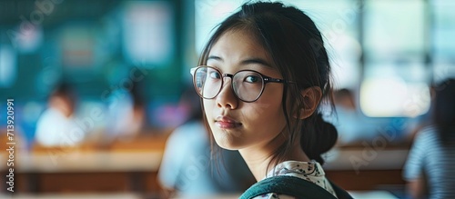 Cute asian girl holding glasses in classroom. Creative Banner. Copyspace image photo