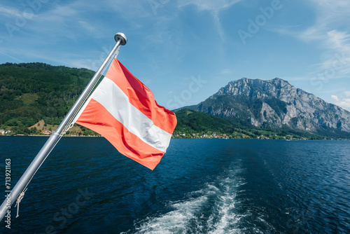 Fotografie austrian flag on the stern of a ship on lake traunsee in austria