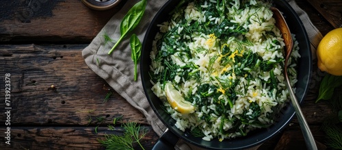 close up of Spanakorizo Greek spinach and rice pilaf with lemon dill scallion in frying pan on dark wooden table horizontal view from above. Creative Banner. Copyspace image