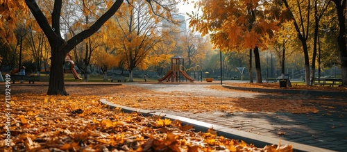 Empty playground roundabout surrounded by fallen autumn leaves in park. Creative Banner. Copyspace image