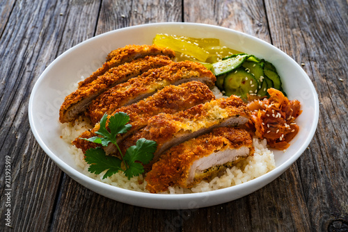 Torikatsu - crispy Japanese chicken cutlet with white rice and marinated vegetables on wooden table 
