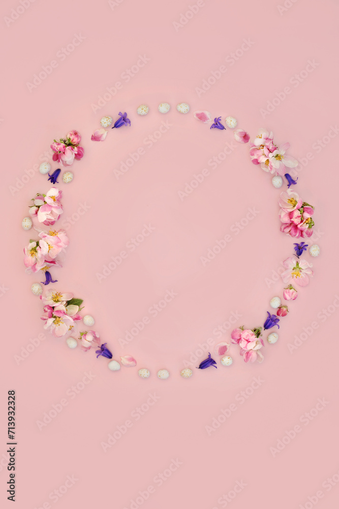 Floral wreath for Easter with mini eggs, bluebell flowers and apple blossom. Abstract design for card, logo, gift tag or invitation on pink background.