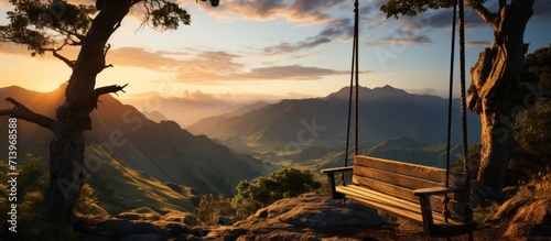 Empty swing on top of hill overlooking beautiful view with mountains and valley at sunset