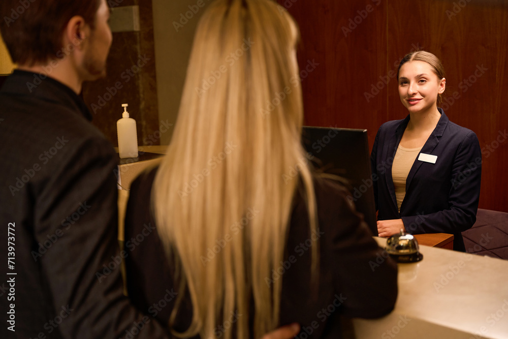 Smiling receptionist greeting young couple at reception desk Smiling receptionist greeting young couple at reception desk