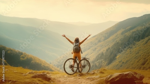 Happy woman with open arms on bike high in mountains. Travel summer lifestyle. photo
