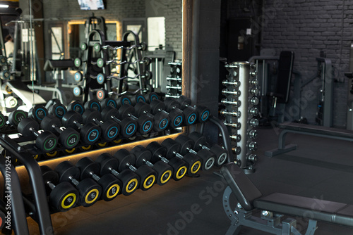Dark gym with focus on various dumbbells. Get fit with workout in this intense atmosphere, surrounded by weights