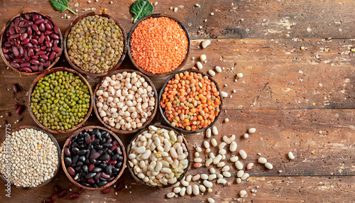 Top view of various bowls of legumes of various types and colors on a dark wooden kitchen table. Healthy food concept and detox or vegan menu. World Pulses Day. photo