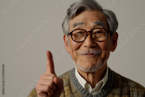 Senior adult Japanese man against white wall. Pointing senior man. Wagging finger  serious mature man. Senior man asking to focus with his forefinger. Senior man having good idea
