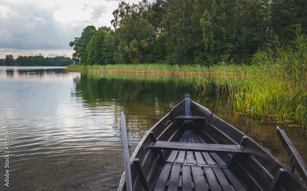 Wooden boat with oars on the shore of a forest lake. Summer holidays Wooden boat with oars on the shore of a forest lake. Summer holidays